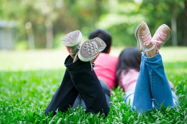 Two teens laying on the grass